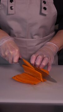 The cook's hands are cutting carrots in close-up. Cooking healthy food and homemade dishes