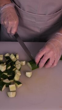 The cook is slicing a fresh cucumber for the salad. We prepare healthy food and homemade meals