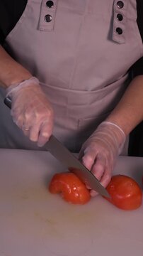 The cook is slicing red tomatoes for the salad. We prepare healthy food and homemade meals