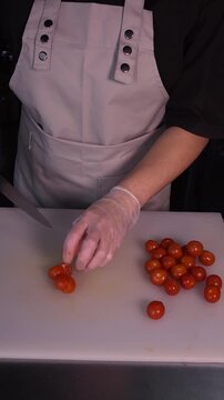 The cook is slicing red cherry tomatoes for the salad. We prepare healthy food and homemade meals