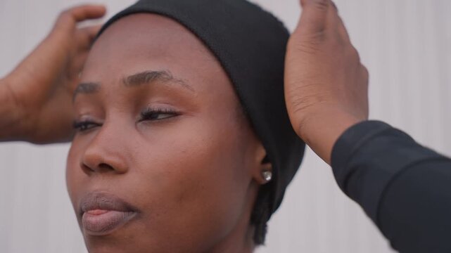 Calm lady adjusts scarf thoughtfully. Focused woman meticulously prepares for her upcoming workout session. Poised lady carefully adjusts her scarf and gets ready to engage in physical activity