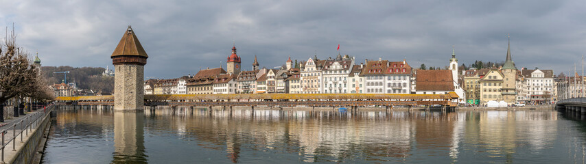 Fototapeta premium medieval wooden bridge with tower, mirroring in the water, center of Lucerne, a landmark of the city, old town of Lucerne, Switzerland, surrounded by beautiful old houses with shutters and paintings.