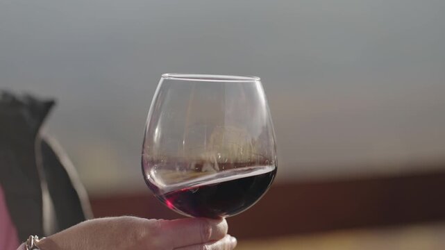 A close-up shot of a sommelier spinning a glass of red wine, cinematic isolated slow motion shot