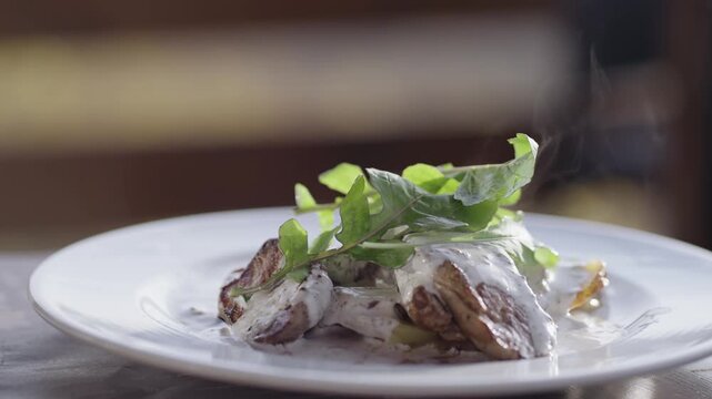 Grilled sliced beef steak with sauce, and rosemary on a white plate and hot steam, cinematic isolated slow motion shot