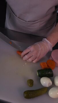 The cook's hands are cutting carrots in close-up. Cooking healthy food and homemade dishes
