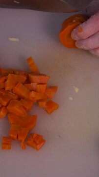 The cook's hands are cutting carrots in close-up. Cooking healthy food and homemade dishes