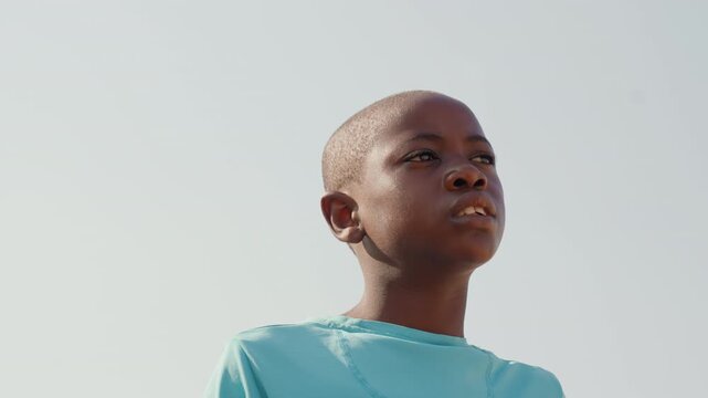 Hopeful young athlete. Boy confidently gazing at sky. Confident youth looks upward with optimistic anticipation. Hopeful young athlete gazes into bright sky filled with optimism and ambition