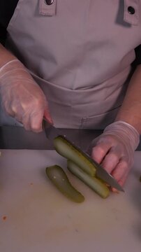 The cook is slicing a pickle for a salad. We prepare healthy food and homemade meals