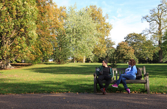londres pareja de j&oacute;venes chico y chica turistas sentados en un banco de madera de un parque c&eacute;ntrico para descansar IMG_2437-as26