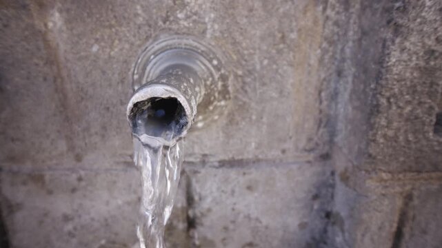 Ancient pipe drinking fountain of fresh mountain water flowing in slow motion