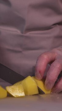 The cook is slicing potatoes for the soup. Preparation of the first courses