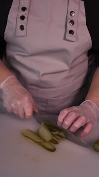 The cook is slicing a pickle for a salad. We prepare healthy food and homemade meals