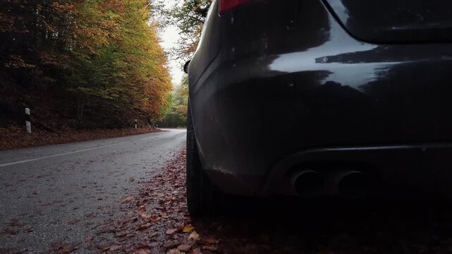 Broken car with flashing orange blinker turn emergency ight parked on side of rural road in mountian autumn forest