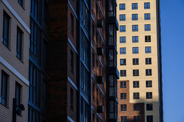 Fototapeta premium Modern residential buildings with contrasting facades under clear blue sky