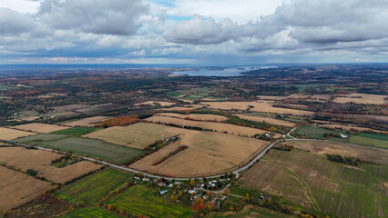 Serene aerial view of a rural landscape with patchwork fields, trees, and a cloudy sky, evoking a sense of peacefulness and natural beauty, Port Hope, Ontario, Canada