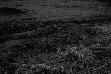 Obraz premium Soil texture with tire tracks and dry grass in agricultural field