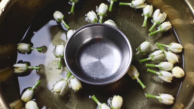 Jasmine Flower Buds Floating In Water Around A Metal Bowl image photo