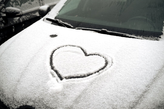 Heart on the hood of a snow-covered car. High quality photo