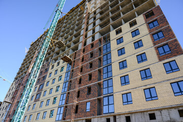 Fototapeta premium High-rise building construction with crane and scaffolding