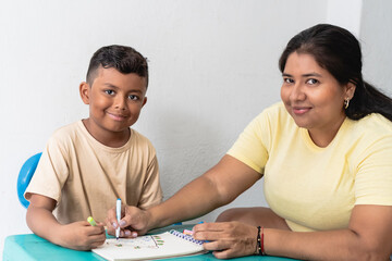 Fototapeta premium Mother and son coloring in notebook learning together