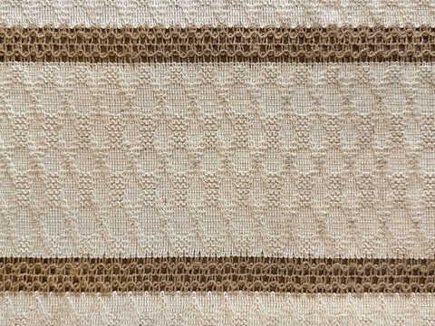 Close up of decorative fabric cloth with horizontal belt and stripes in brown and beige color. Ornamental lace on fabric, with abstract sewn pattern. For table runner, Seamless background texture.