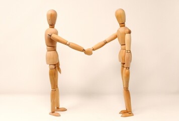 Business concept represented by two wooden figures completing a professional handshake transaction.