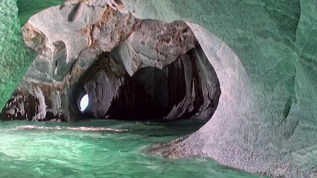 Explore stunning Marble Caves of Patagonia, where vibrant emerald water meets intricately carved rock formations. Sunlight penetrates, creating radiant spectacle. Truly magnificent natural display.