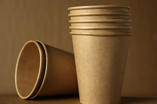 Stacked paper cups on a brown background with one cup tipped over
