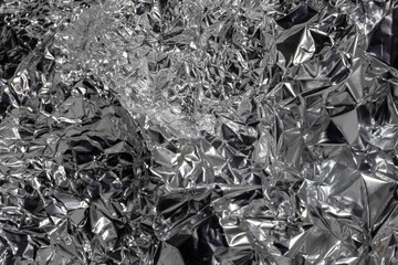Crumpled aluminum foil creating abstract silver metallic texture