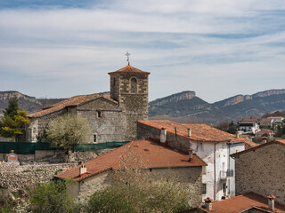 Valdelateja Church and Canyon Cliffs - View of the historic stone church and red-roofed houses of Valdelateja, set against the imposing cliffs of the Ebro Canyon in Burgos, Spain.