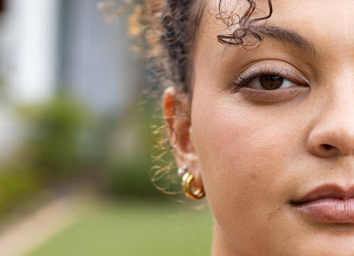 African American woman looking toward camera in yard, showing gold hoop and stud earring