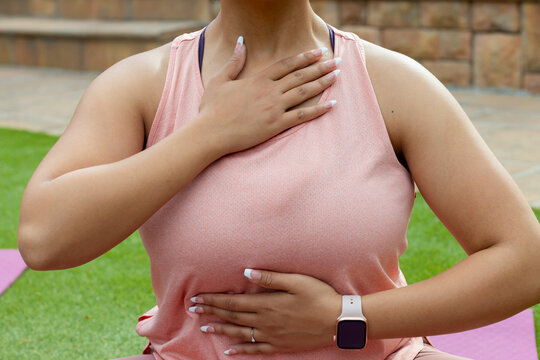 African-American-woman breathing on mat in yard hands-on-chest-belly in tank-straps watch and ring