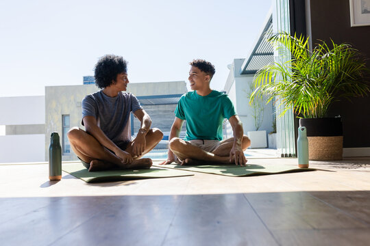 Wooden teardrop pendant resting on white surface, hanging from thin dark cord under studio lighting