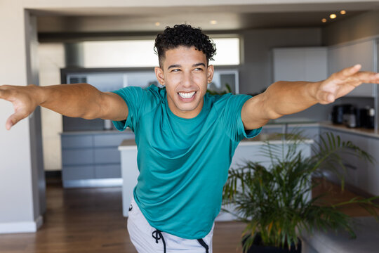 African American man balancing and posing while leaning forward in kitchen near island and plant