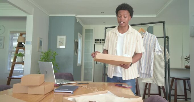 African American man packing boxes at home, opening box, tying twine, attaching shipping tag