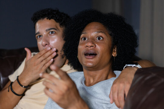 African American couple sitting on leather sofa in living room, wearing grey sweater and nose ring