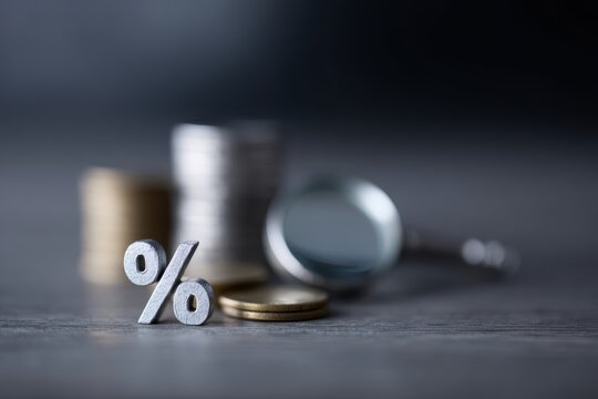 House coins and percentage symbol under magnifying glass, mortgage analysis concept