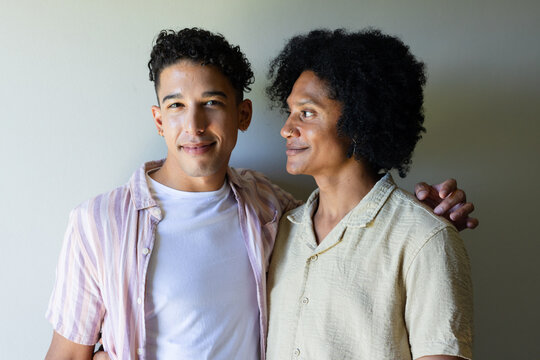 African American men posing by wall wearing pink tee, beige shirt, resting hand on shoulder, stud