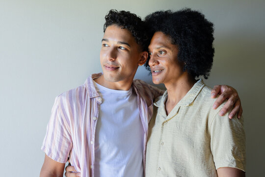 Diverse male friends standing in front of plain light wall, wearing striped shirt, nose ring