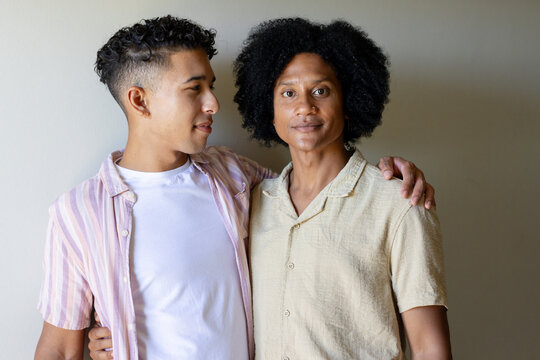 Diverse men standing close in studio, wearing striped shirt, white tee and beige button-up, earring