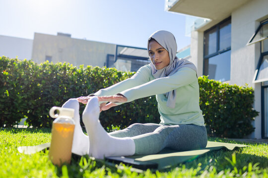 Owner hand holding small hamster in cage while hamster sniffing finger near wheel, bedding