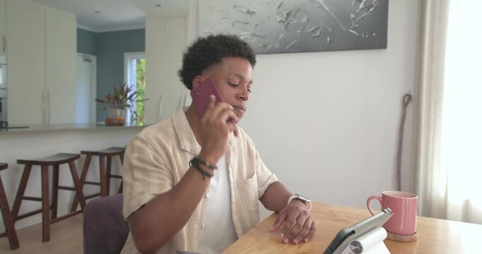 Receiving call, African man holding red smartphone, checking tablet and stack of papers for review