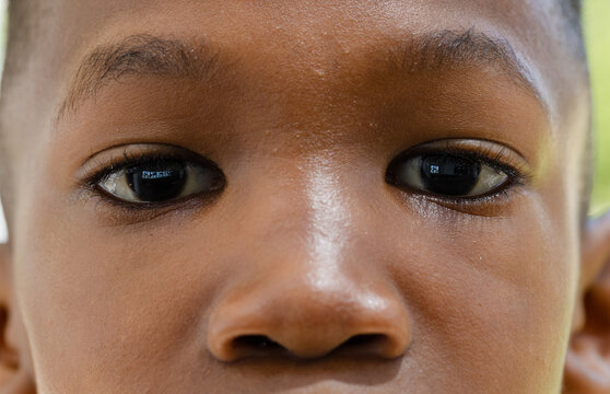 African male youth looking directly at camera in close-up showing window reflection in pupils