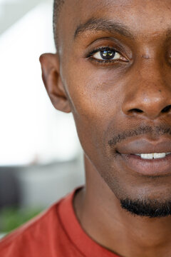 African male facing right, showing trimmed goatee and teeth, wearing red T-shirt in living room
