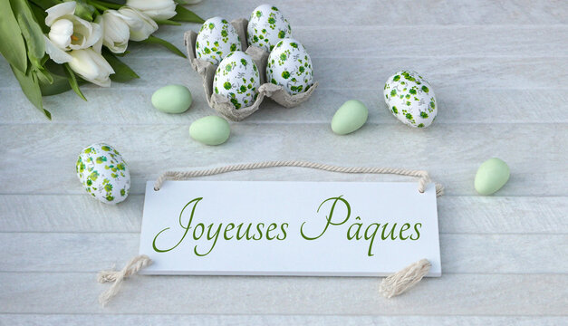 Carte de souhaits de P&acirc;ques : &oelig;ufs de P&acirc;ques d&eacute;cor&eacute;s de fleurs et portant l'inscription fran&ccedil;aise &laquo; Joyeuses P&acirc;ques &raquo;.