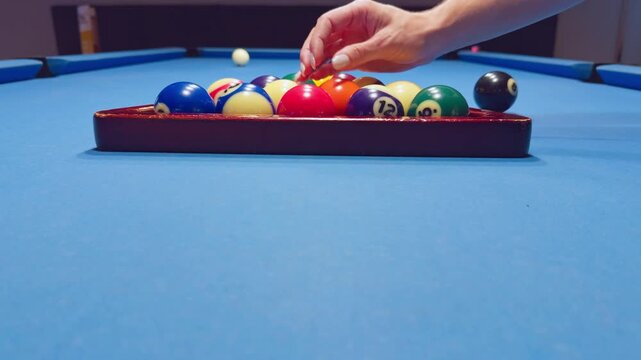 Woman Hand Picking Pool Ball Inside Triangle Rack On Blue Felt Table Before Game Start