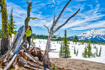A woman stands in front of a tree stump in a snowy field © ExploringandLiving