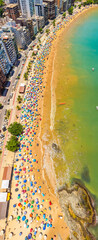 Obraz premium Aerial view of crowded Praia do Morro beach during summer tourism season in Guarapari Brazil