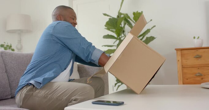 African American man seeing package at home lifting opening inspecting inner box checking order