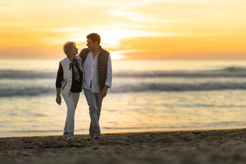 Senior couple walking on beach during sunset